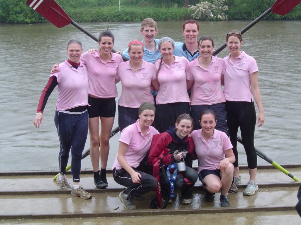 Hertford women's rowing crew stood next to the river with a set of oars