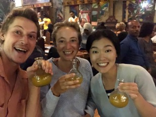 Three of the cyclists holding up unusually shaped glasses, filled with a golden liquid