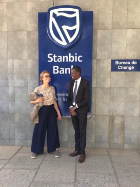 Michelle stood with a man next to a sign for 'Stanbic Bank'