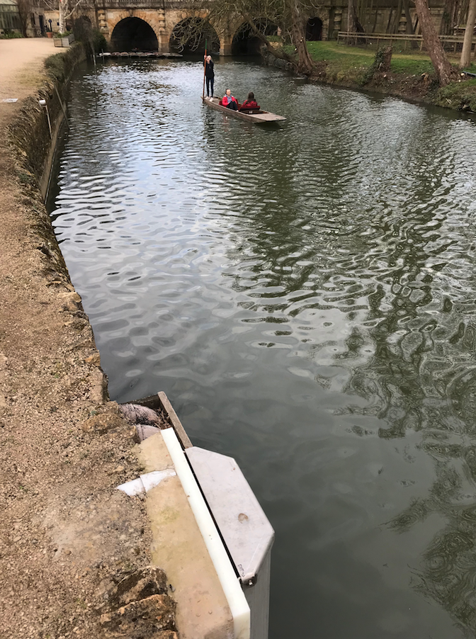 The River Cherwell, with a device built in to the riverbank in the foreground, and punters in the background