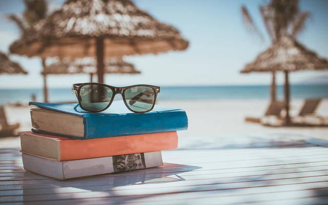 Summer-themed picture of books near a beach