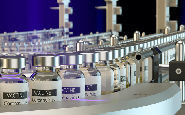 Bottles of COVID-19 vaccine make their way down a manufacturing assembly line