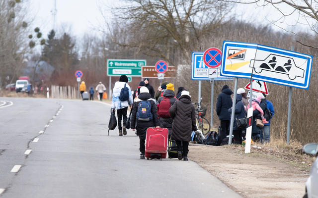 Ukrainian refugees walking along a road in 2022