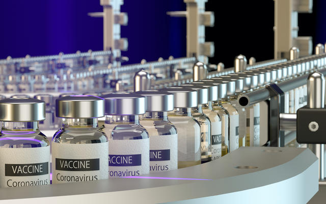 Bottles of COVID-19 vaccine make their way down a manufacturing assembly line