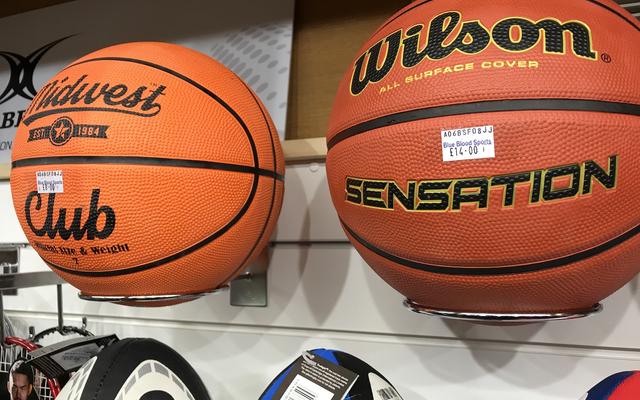 Two basketballs on a shelf in a sports shop, with the price stickers with the shop name 'Blue Blood'