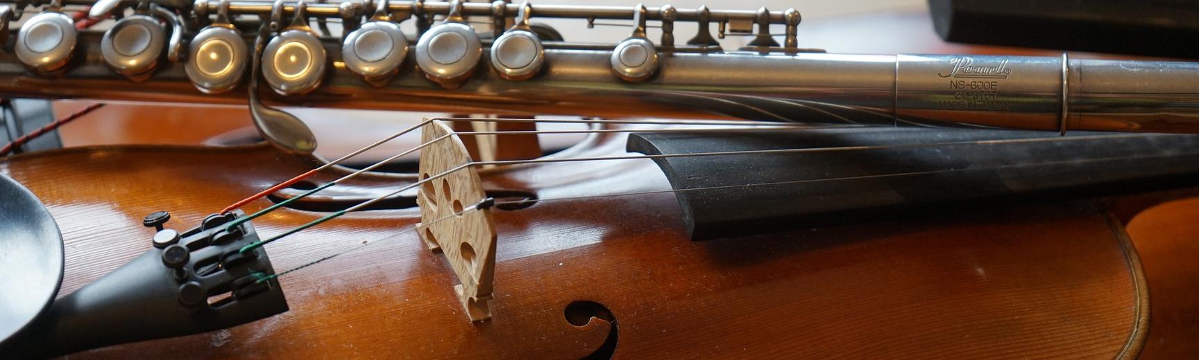 A flute lying on a violin, on top of a double bass