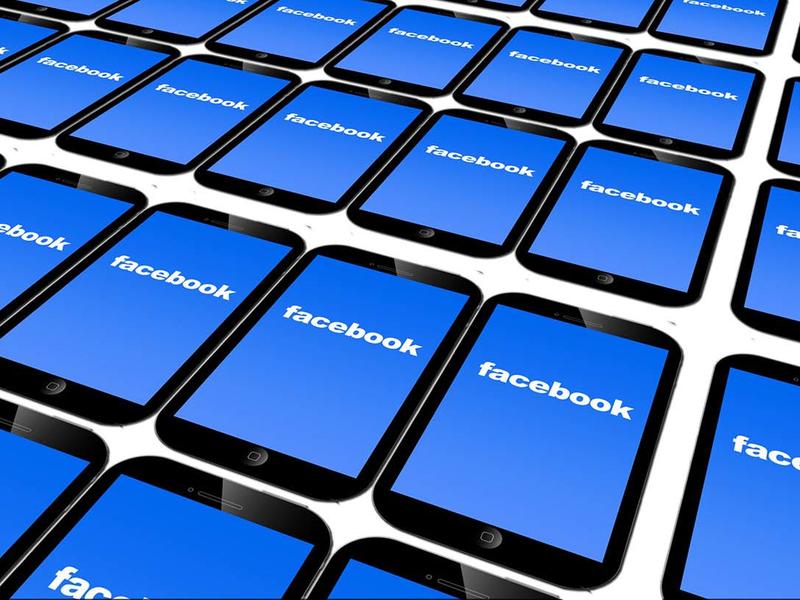 Many mobile devices, stretching off the edge of the image in all directions, all showing the Facebook logo