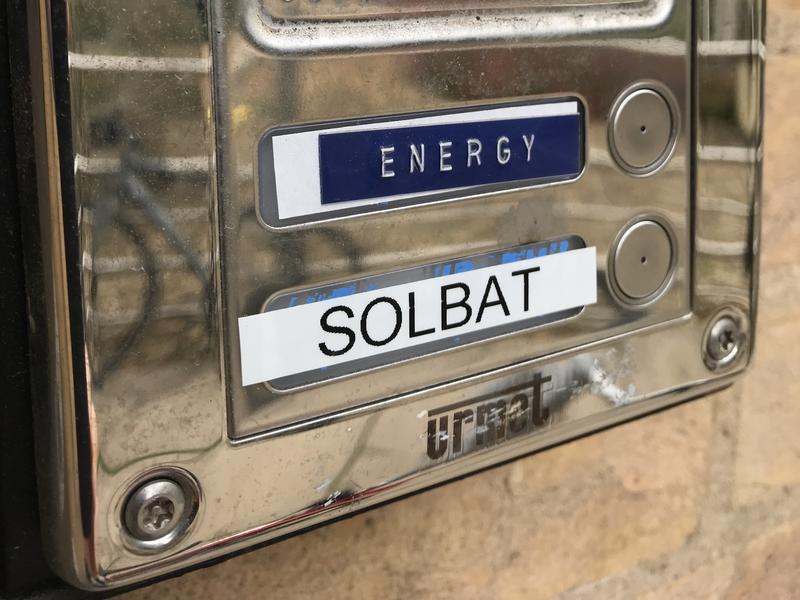 An intercom system on the outside of a building, with 'Dept of Materials' at the top, and two buttons below, one for calling 'ENERGY', the other for 'SOLBAT'