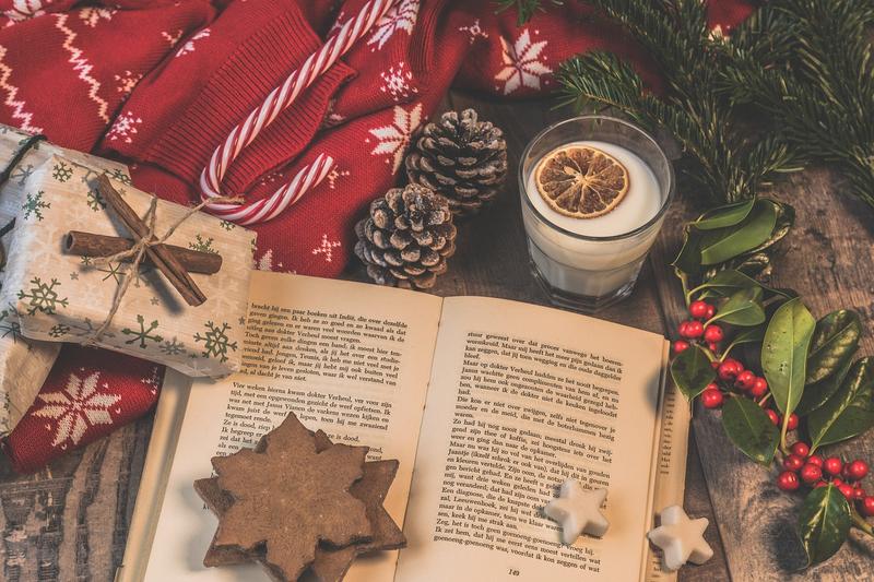 A book surrounded by Christmas gifts, pinecones and holly