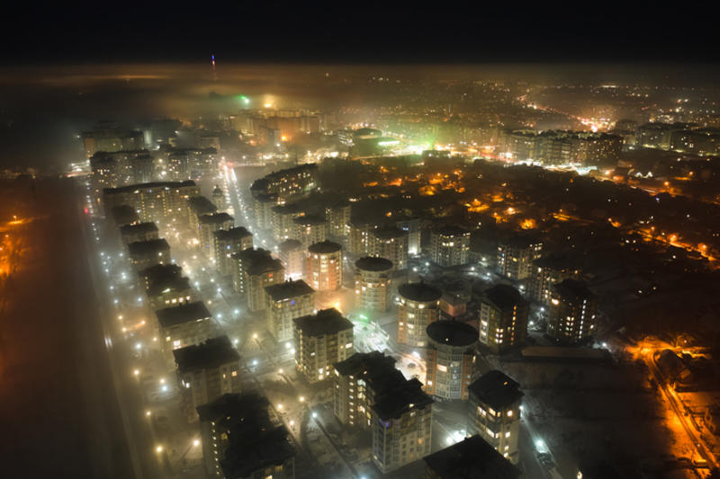 Aerial view of high rise apartment buildings and bright illuminated streets in Ivano-Frankivsk city, Ukraine residential area at night. Dark urban landscape