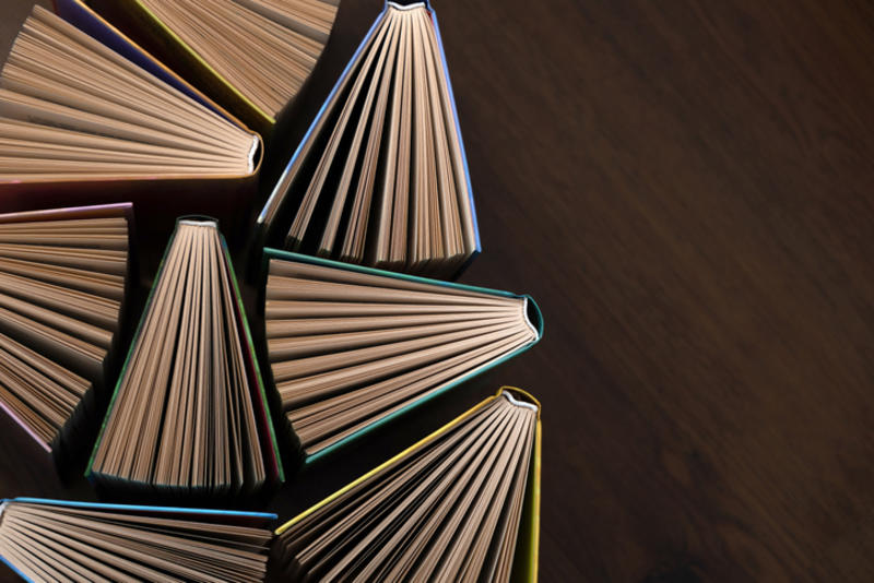 Eight books viewed from above, their pages fanned out