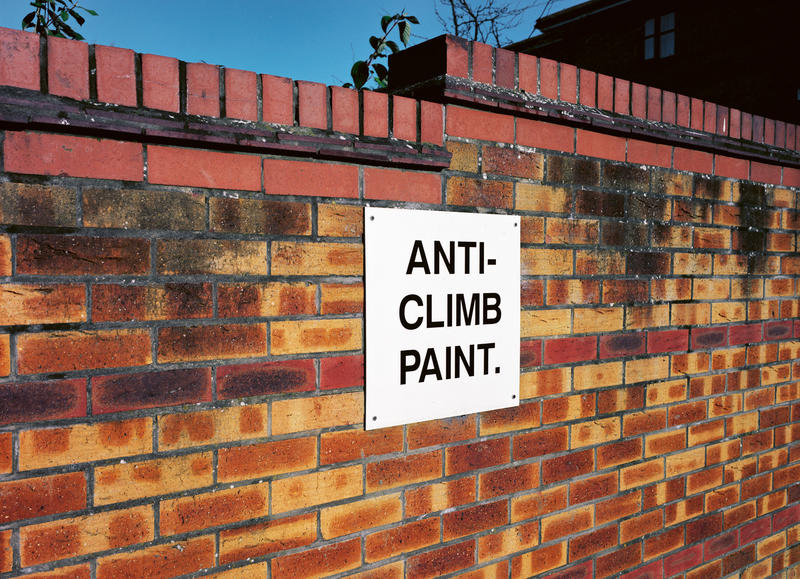 Brick wall with sign 'Anti-Climb Paint'