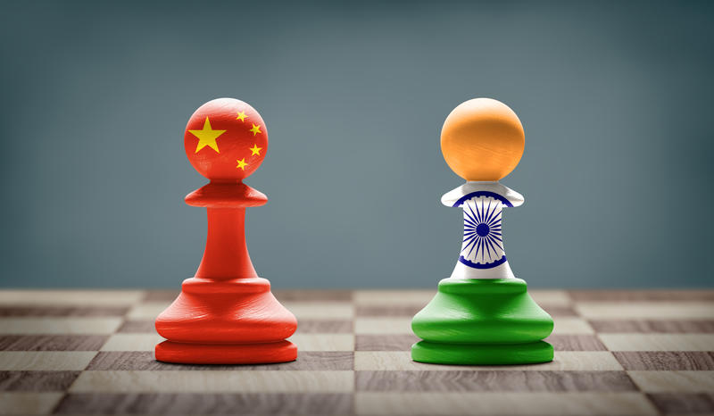 Two chess pawns - one is painted in the colours of the flag of China, the other in the colours of the flag of India