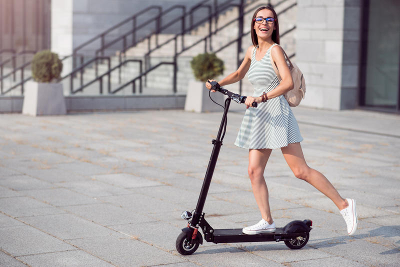 A smiling woman riding an electric scooter