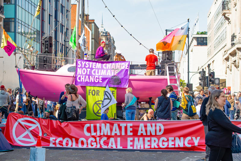 Particpants in the Extinction Rebellion demonstrations in London, holding banners on a pink boat, parked to block a street 