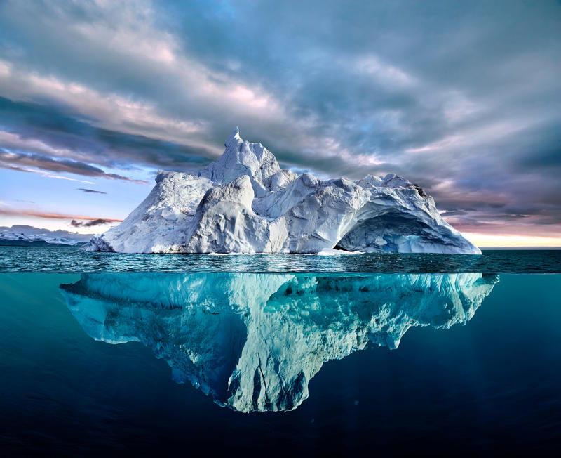 A large ice berg, with parts above and below the water level