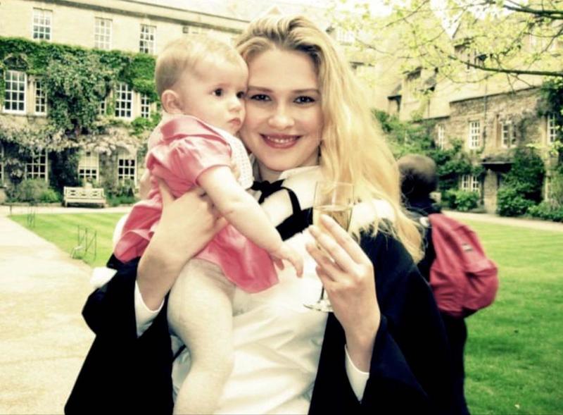 Irra Ariella Khi after her graduation ceremony, stood in a college quad, holding a baby