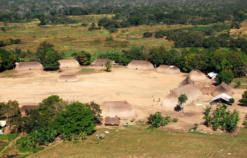 An aerial view of a village in a large clearing within a rain forest