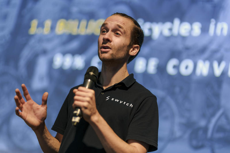 Oliver Montague speaking while holding a micrphone