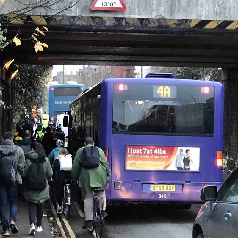 Traffic congestion on Botley Road, beneath the railway bridge, with cyclists' progress stopped by a bus