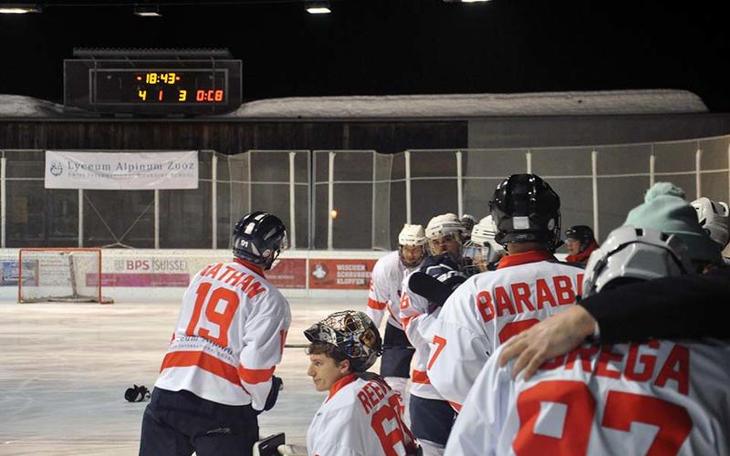 An ice hockey team on a rink, looking disappointed, with a scoreboard showing 4-3 in the background