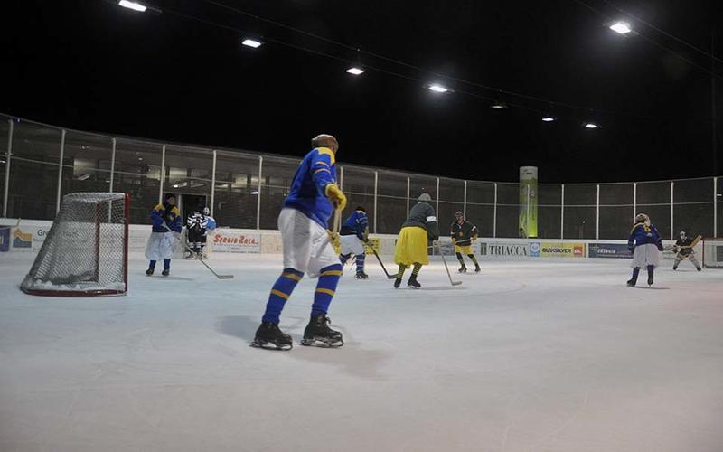 An ice hockey match in progress, with the participants wearing vintage uniforms