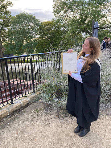 Carys holds up her undergraduate degree certificate