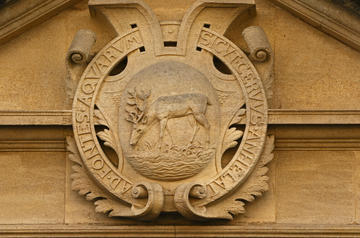 Hertford College Stag in centre with Latin writing around it. Sandstone colour.