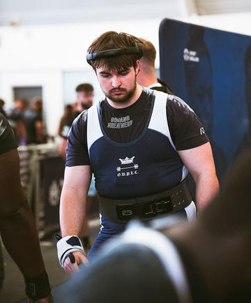 Will James wearing his OUPLC uniform and over-ear headphones at the BUCS Powerlifting Championships